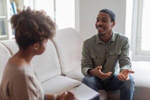 smiling man sits on a couch with a woman and discusses alcohol addiction treatment