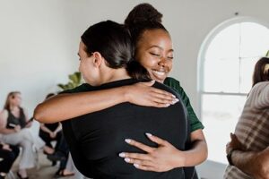 two women in embrace with a hug while working through some issues in their cognitive-behavioral therapy