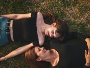 women in black tops laying on the ground looking at each other mother and daughter healing their relationship